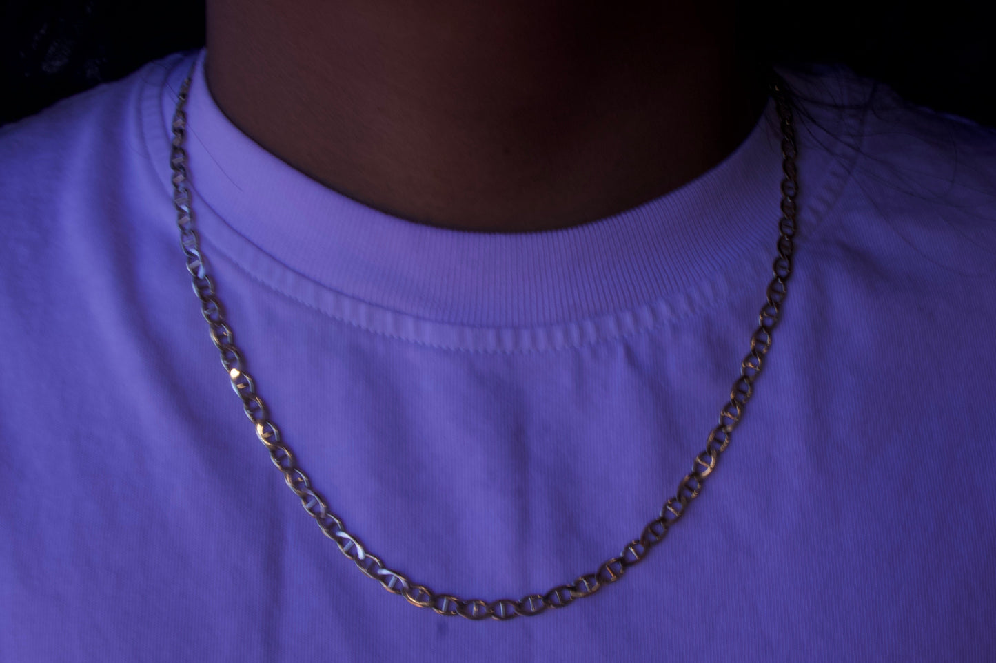 Person wearing a purple shirt with a chain necklace