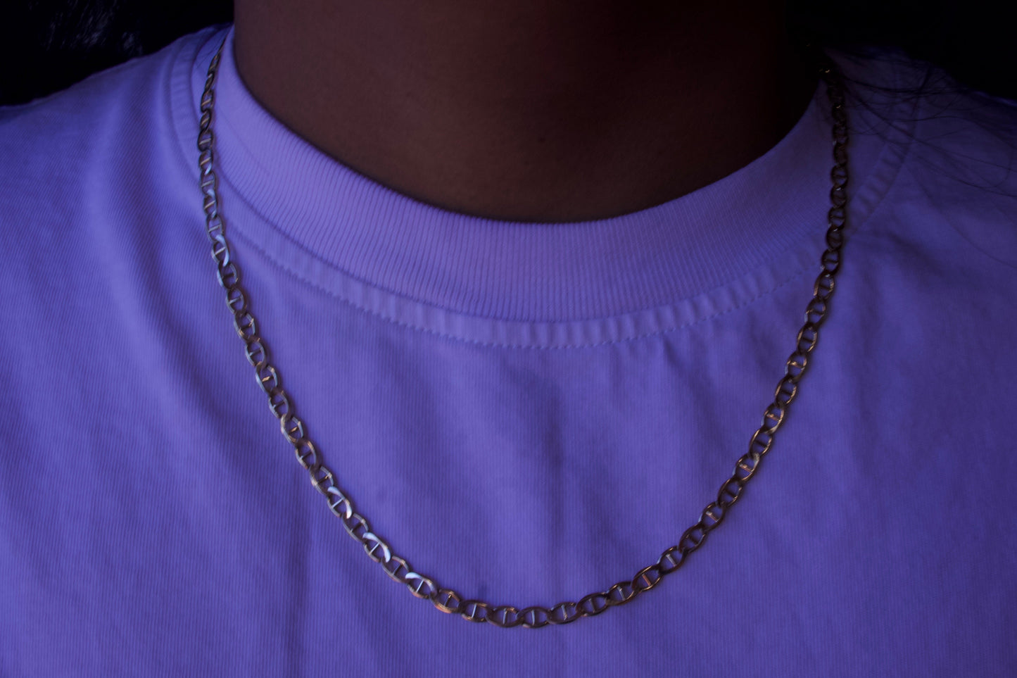 Person wearing a purple shirt with a chain necklace