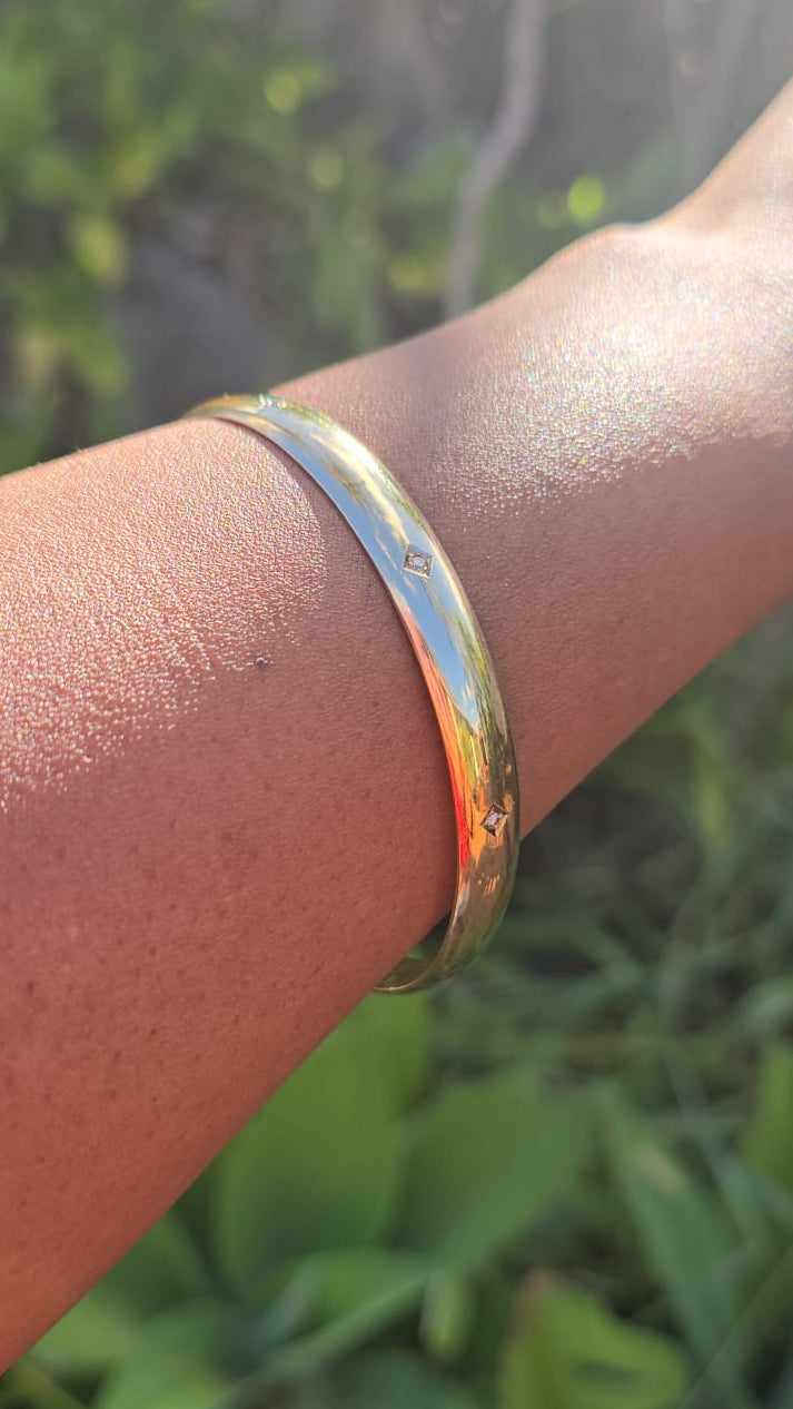 Gold bracelet on a wrist with a blurred natural background