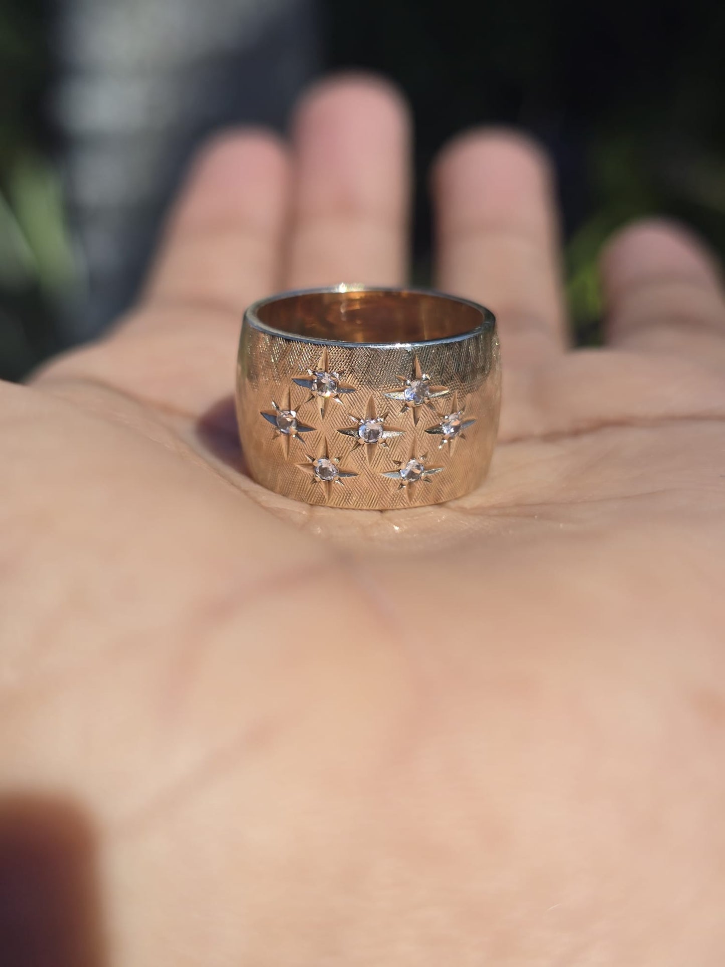 Gold ring with star designs on a hand