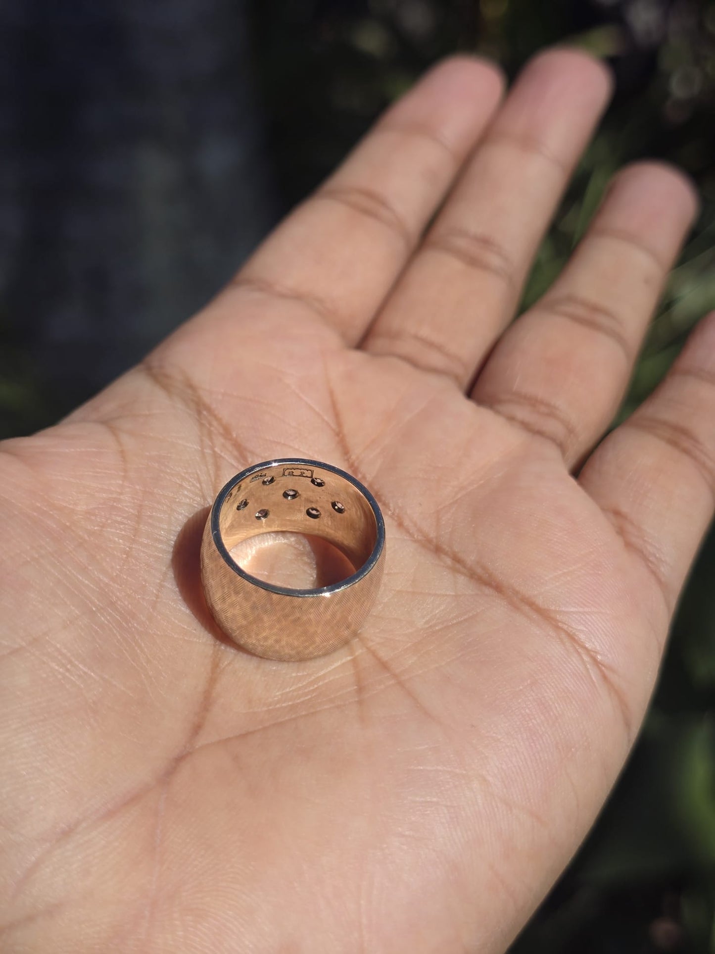 Gold ring with embedded stones on a person's palm