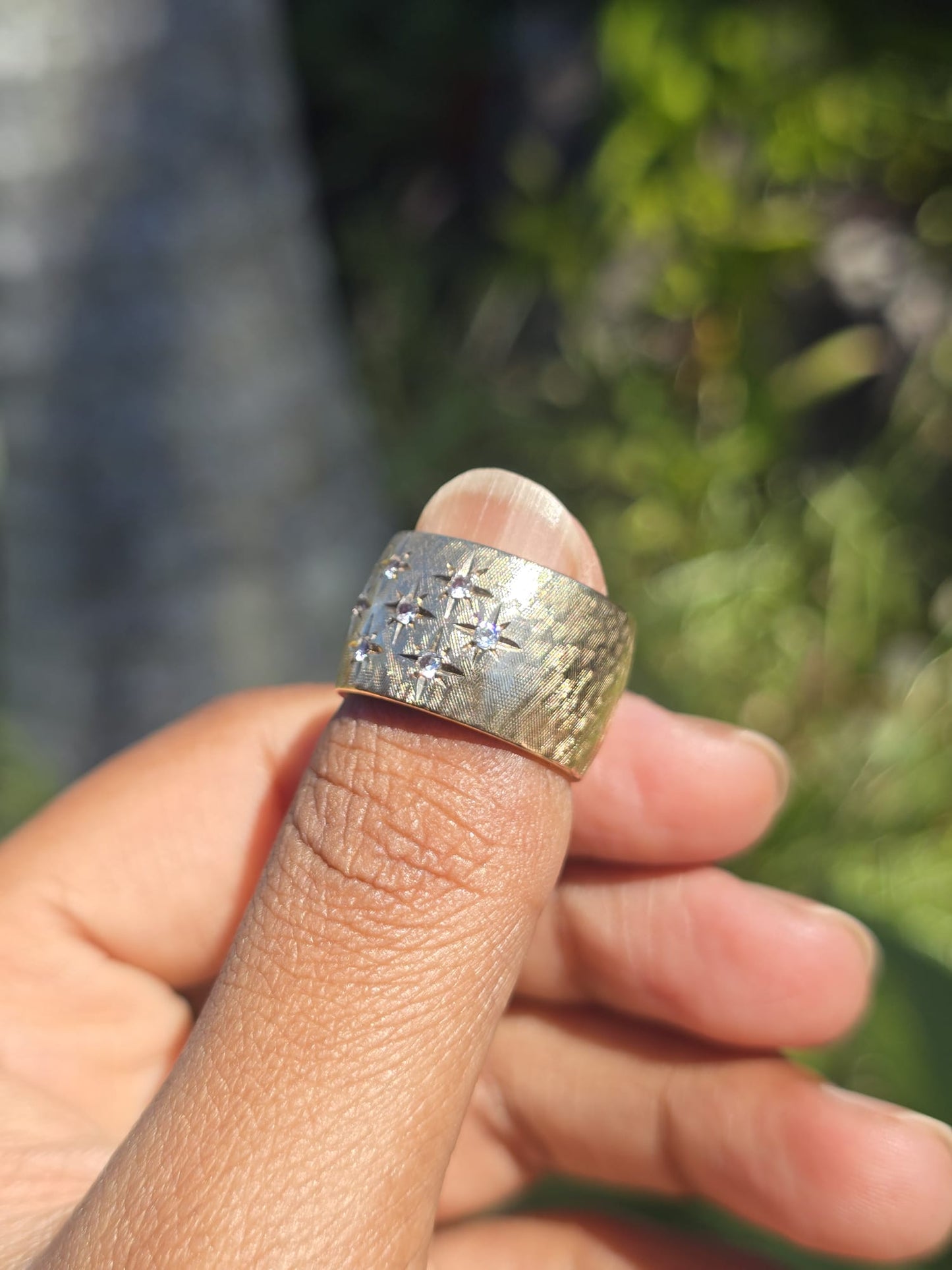 Gold ring on a finger with a blurred natural background