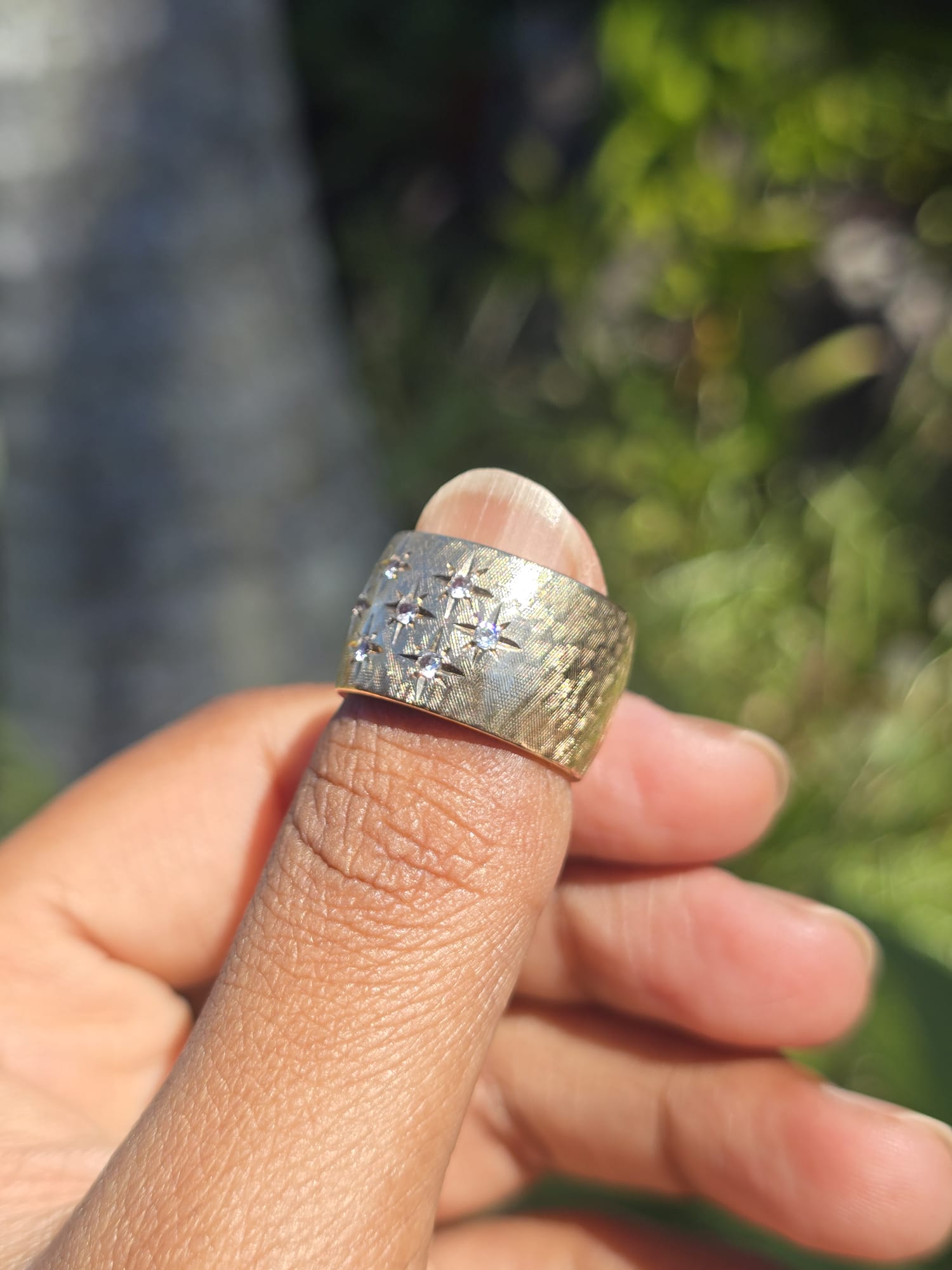 Gold ring on a finger with a blurred natural background