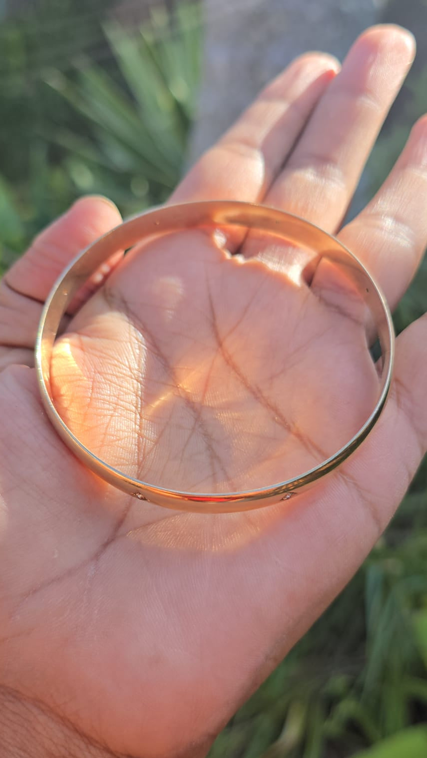 Rose gold bangle on a hand with a blurred natural background