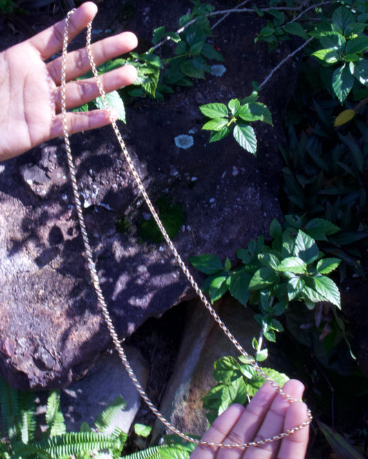 Hand holding a string of beads with a natural background of rocks and plants