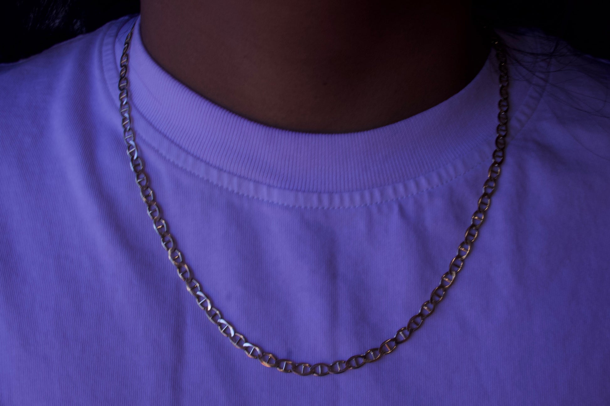 Person wearing a purple shirt with a chain necklace