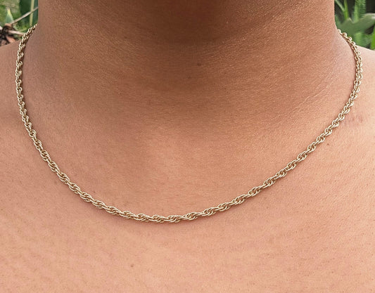 A close-up of a person's neck and upper chest wearing a delicate gold chain necklace.