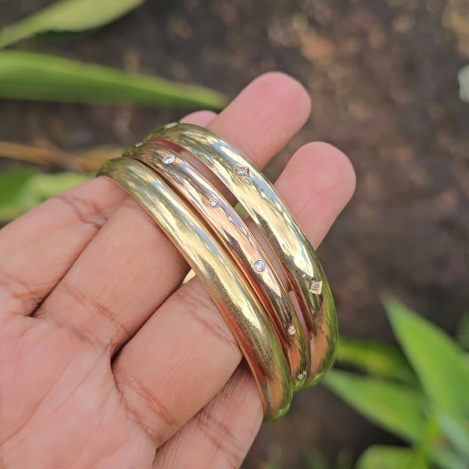 Gold bangles on a hand with a blurred natural background